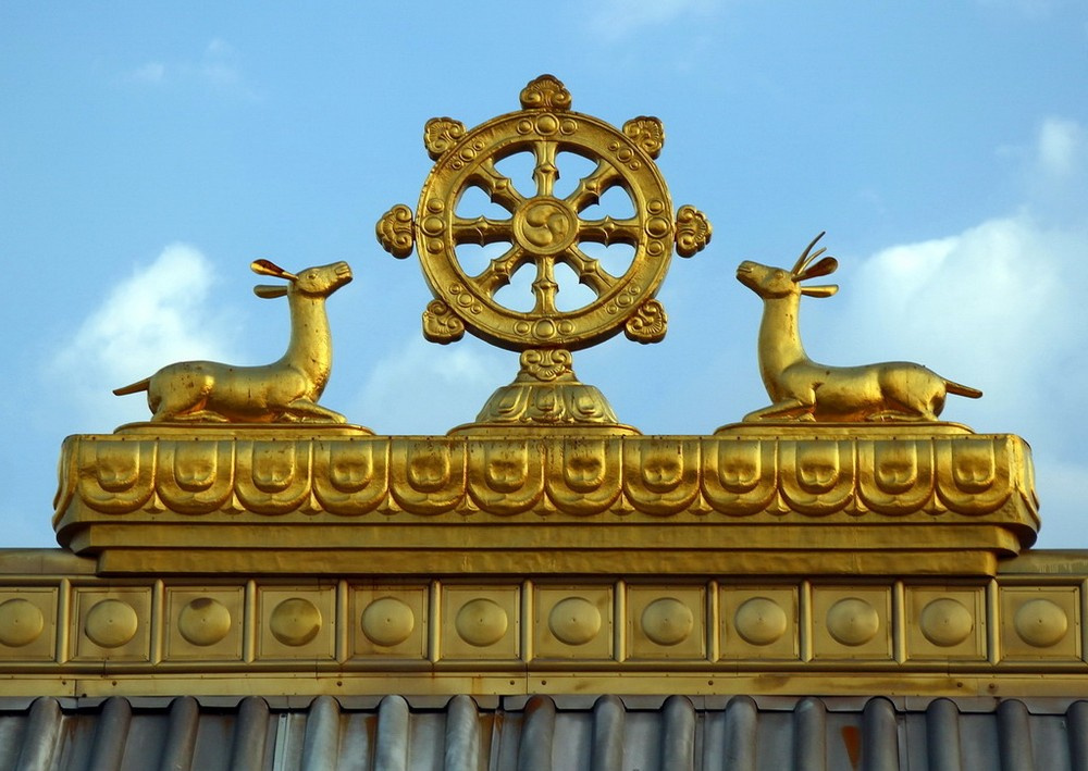 Крышу храма украшают две золотые лани и колесо дхармы